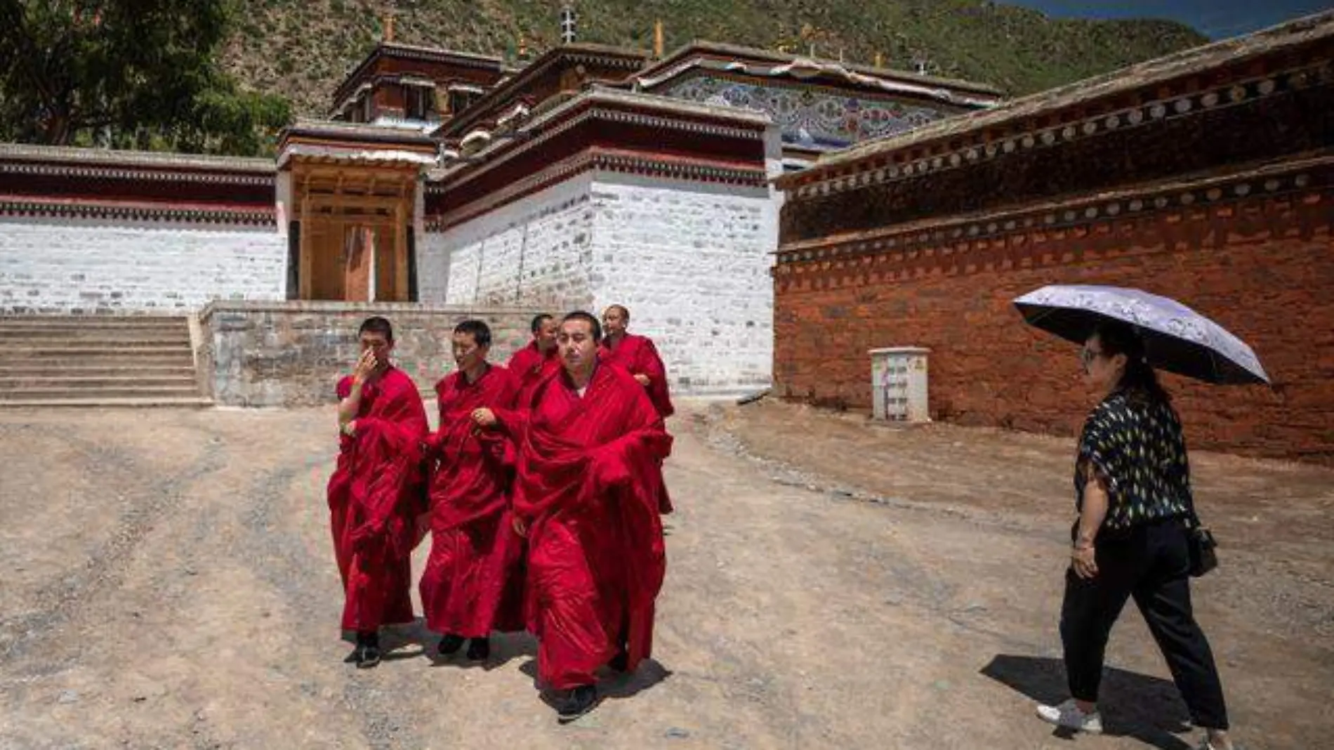 una turista pasa frente a un grupo de monjes